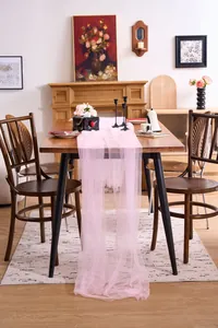 Close-up of pink tulle fabric draped elegantly over a rustic wooden dining table
