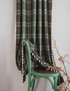 Close-up of green and brown plaid wool curtains featuring decorative white tassels