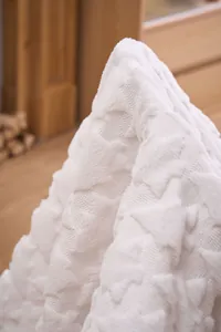 Close-up of the intricate carved Christmas tree pattern on the soft white plush blanket
