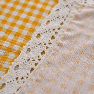 Detail view of yellow and white gingham tablecloth with decorative white lace edge