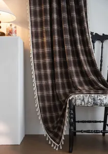 Detailed view of brown plaid curtain with tassel trim and cozy French vintage draping.