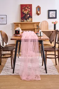Elegant pink tulle table runner draped over a wooden dining table in a cozy home setting