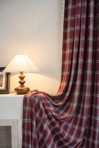 Detail of red plaid French curtains with white fringe tassels in a cozy warm interior