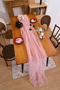 Long elegant pink sheer tulle fabric runner draped on a rustic wooden dining table