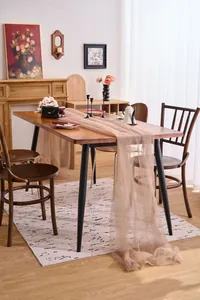 Close-up detail of champagne tulle mesh fabric draped elegantly over a wooden dining table