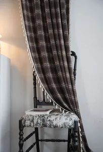 Close-up detail of a brown plaid French style curtain with elegant cream tassel edges