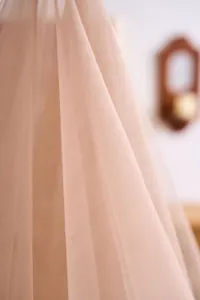 Macro detail of soft pink tulle fabric showing fine mesh texture for wedding drapes