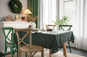 Green plaid Christmas tablecloth on a wooden table in a festive dining room setting