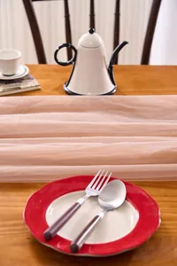 Close-up view of a soft pink tulle table runner draped on a wooden table for wedding decor
