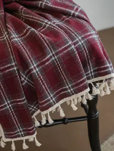 Close-up of red and grey plaid woolen fabric with elegant cream tassel fringe details
