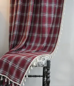 Detail of red French plaid wool curtain with white tassel fringe in a cozy setting