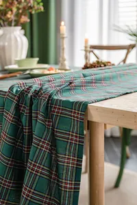 Detail showing the drape of a green Christmas plaid tablecloth on a wooden table