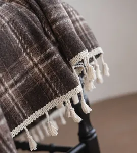 Close-up of coffee brown plaid curtain with decorative white tassel fringe details.