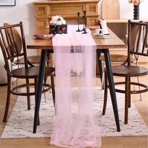 Elegant pink tulle mesh fabric runner draped on wooden table for wedding and party decorations