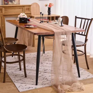 Elegant champagne tulle table runner draped on a wooden dining table for party decor.