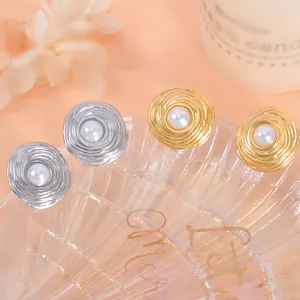 Detailed macro view of spiral titanium steel earrings with pearl center in gold and silver.