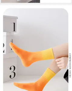 Detailansicht der leuchtend orange-gelben Kompressionssocken mit Farbverlauf am Bein.