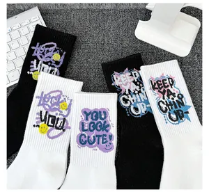 Vue détaillée de chaussettes en coton noir et blanc avec texte graffiti et smileys.