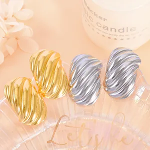 Macro view of gold and silver plated twist wave earrings with high-shine finish