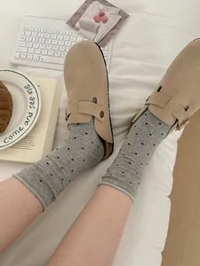 Close-up of women's grey polka dot cotton mid-calf socks with elegant rolled-edge design