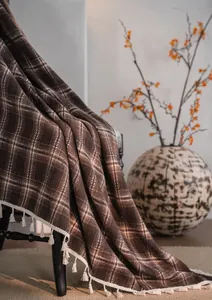 Close-up view of coffee plaid French curtain fabric featuring elegant white fringe tassels.