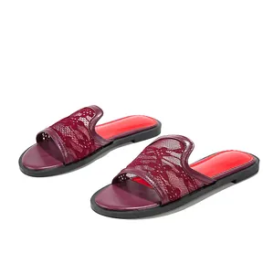 Vue détaillée de sandales plates pour femmes avec tige en dentelle bordeaux et semelle rouge.
