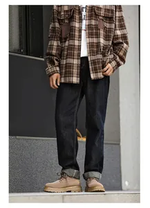 Men's tan suede work boots styled with brown plaid shirt and dark jeans in street view