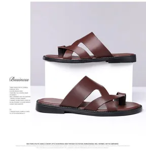 Detailansicht der braunen Leder-Herrensandalen auf weißen Podesten am Strand