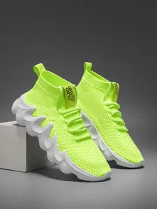 Detail view of neon green fly-knit sock sneakers with white wavy chunky outsoles.