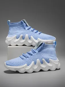 Detailed view of light blue breathable fly-knit sports sneakers with wavy white soles