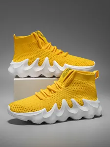 Detail of bright yellow knit high-top sneakers with chunky white wave-shaped soles.