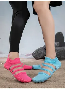 Detailed view of breathable pink and blue mesh water shoes worn on a sandy beach