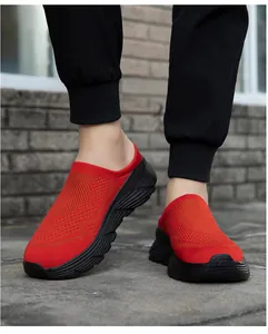 Close-up of red breathable mesh slip-on sneakers with thick black soles worn outdoors.