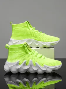 Side view of neon green high-top flyknit sneakers with thick wavy white soles.