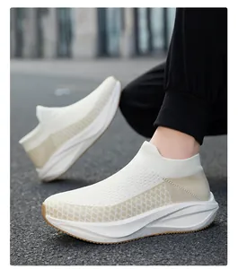 Detailed close-up of white and beige fly-knit slip-on sneakers worn on a street