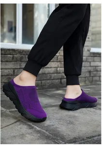 Close-up of purple breathable knit slip-on mules with thick black soles worn outdoors.