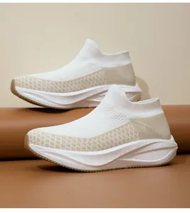 Detailed side view of white flyknit slip-on sneakers with breathable tan mesh panels