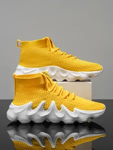 Detailed view of yellow knit sneakers with wavy white soles on reflective surface