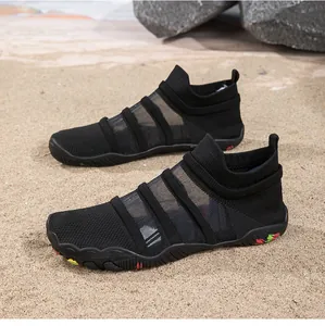 Close-up detail of breathable black mesh water shoes placed on a sandy beach background