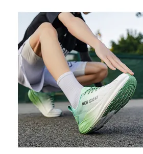 Detailaufnahme von grün-weißen atmungsaktiven Mesh-Laufschuhen auf einem Sportplatz.
