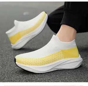Detail shot of white and yellow breathable fly-knit slip-on sneakers on pavement
