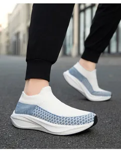Side detail of white and blue breathable knit slip-on sneakers worn in an outdoor setting.