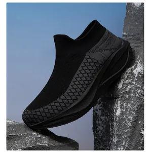 Macro detail of black fly-knit sock shoe texture perched between grey stones