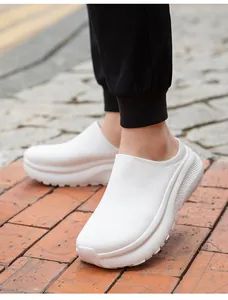 Close-up of white platform sock-style mules on brick pavement