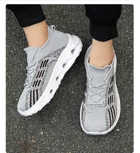 Vista dettagliata di scarpe sneaker a calzino in maglia grigia indossate su suolo d'asfalto