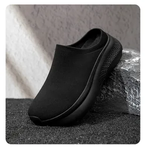 Close-up of black knit mule shoe with textured thick sole on a rocky background.