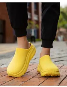 Macro view of bright yellow knit slip-on sneakers with thick textured sole on pavement.