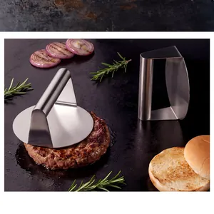 Macro view of a stainless steel burger press flattening a meat patty on a dark grill