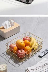 Modern golden iron wire storage basket styled as a fruit bowl on a marble surface