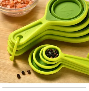 Close-up of foldable green silicone measuring cups and spoons with molded scale markings